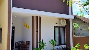 Ein zweistöckiges Haus mit einem Balkon, einem Essbereich mit Stühlen und Topfpflanzen.