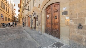 A narrow street with historic buildings, large wooden doors, and a visible number '5' sign. - Uffizi View (Firenze)