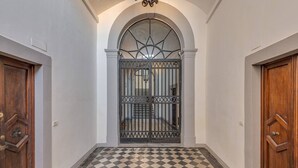 A hallway with a checkered floor, a metal gate, and wooden doors. - Uffizi View (Firenze)
