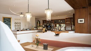 Un hall de hotel con mostrador de recepción, zona de bar y arreglos de asientos.