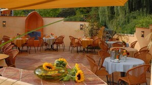 Un patio al aire libre con sillas y mesas de mimbre, algunas con girasoles.