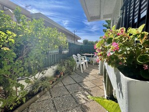 Eine Terrasse mit Blumentöpfen, einem Tisch und Stühlen.