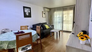 Un salon comprenant une table à manger, des chaises, un canapé, une petite table basse et une fenêtre avec des rideaux.