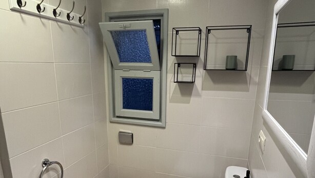 Ein Badezimmer mit Toilette, Waschbecken, Handtuchhalter und einem Fenster.