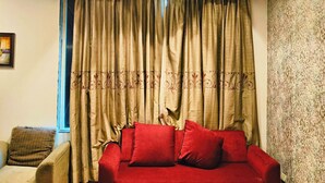 Una sala de estar con un sofá rojo, una mesa de centro de vidrio y una pared con diseño.