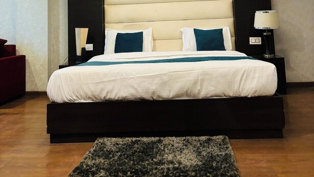 Un dormitorio moderno con una cama grande, un cabecero oscuro y una lámpara de techo.