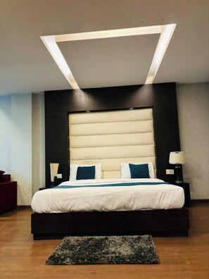 A modern bedroom with a large bed, a dark headboard, and a ceiling light fixture. - HOTEL BILLIONS AIRPORT  (New Delhi)