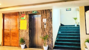 Entrada de un hotel con ascensor, puerta de madera y escalera.