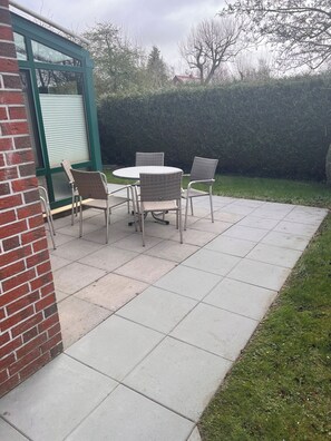 Relax in an outdoor space surrounded by lush greenery and a brick wall.