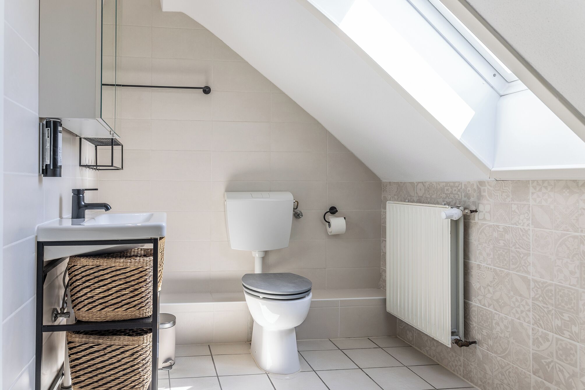 Ein kleines, modernes Badezimmer mit Toilette, Waschbecken und Handtuchwärmer.