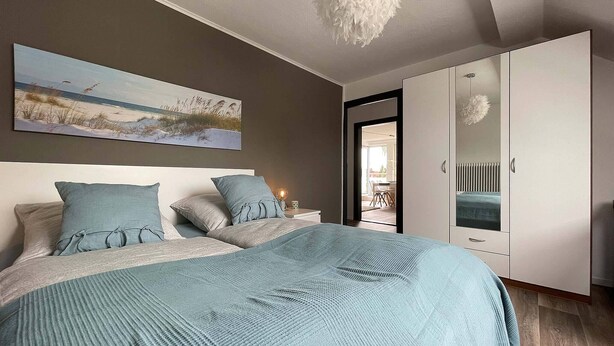Ein Schlafzimmer mit einem Bett, einem Nachttisch, einem Kleiderschrank und einem Bild an der Wand.