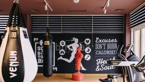 Une salle de sport équipée de matériel d’exercice, d’un sac de frappe et décorée de motifs inspirants sur les murs.