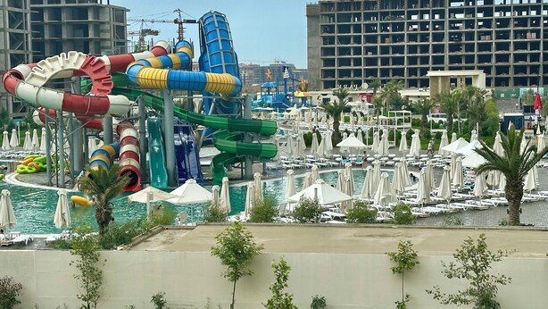 Un parc aquatique doté de nombreux toboggans et d’un espace piscine avec des chaises longues et des parasols.