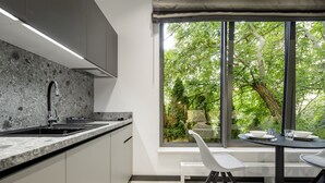 A modern kitchen with a granite countertop, a built-in sink, and a window overlooking a garden. - Apartamenty L11 (Poznan)