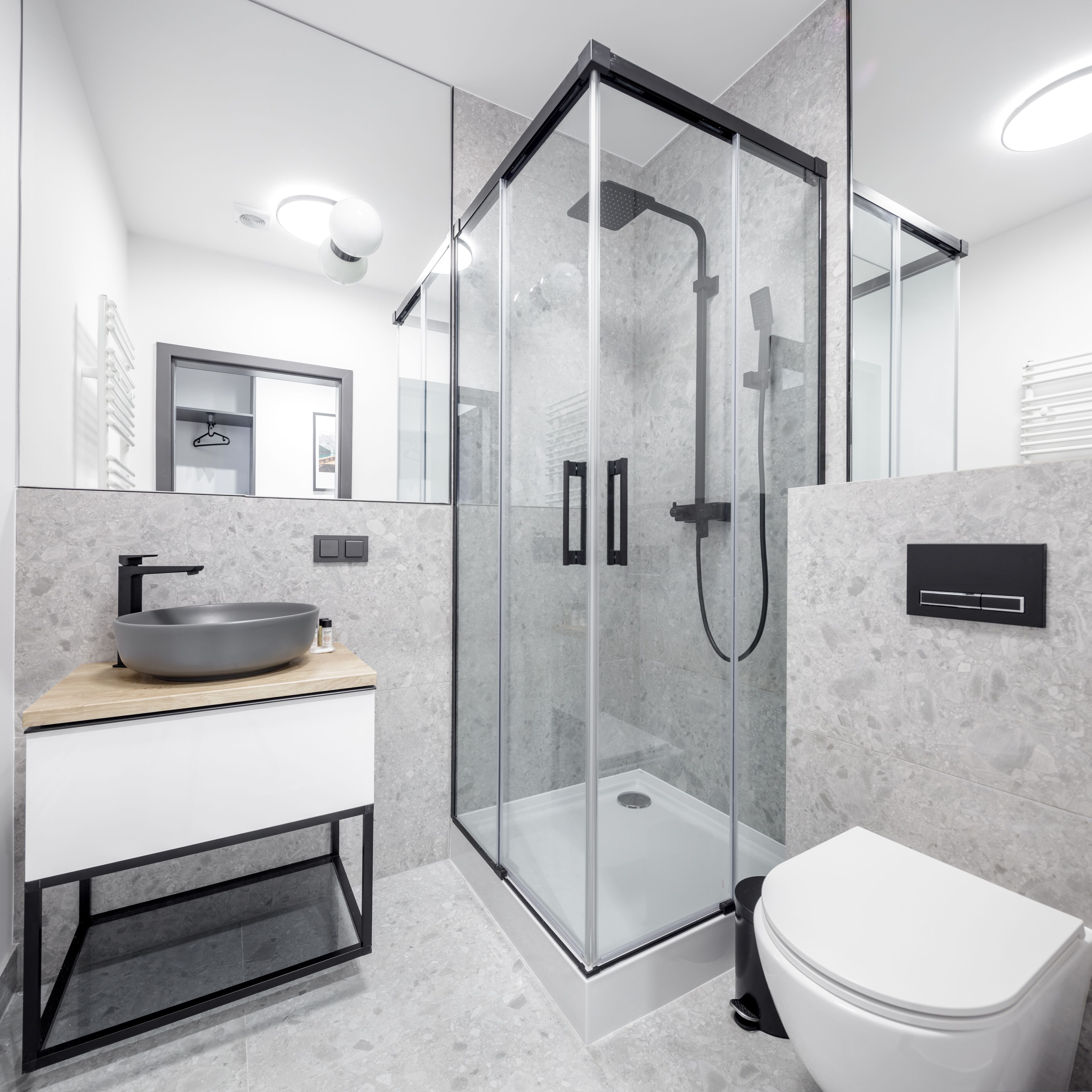 A modern bathroom with a glass-enclosed shower, a white toilet, and a wooden vanity with a vessel sink.