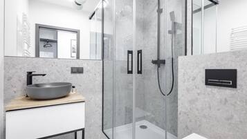 A modern bathroom with a glass-enclosed shower, a white toilet, and a wooden vanity with a vessel sink.