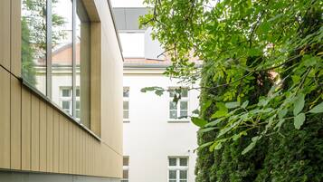 Un bâtiment moderne doté d’une cour étroite, d’une pelouse bien entretenue et d’une haie dense.