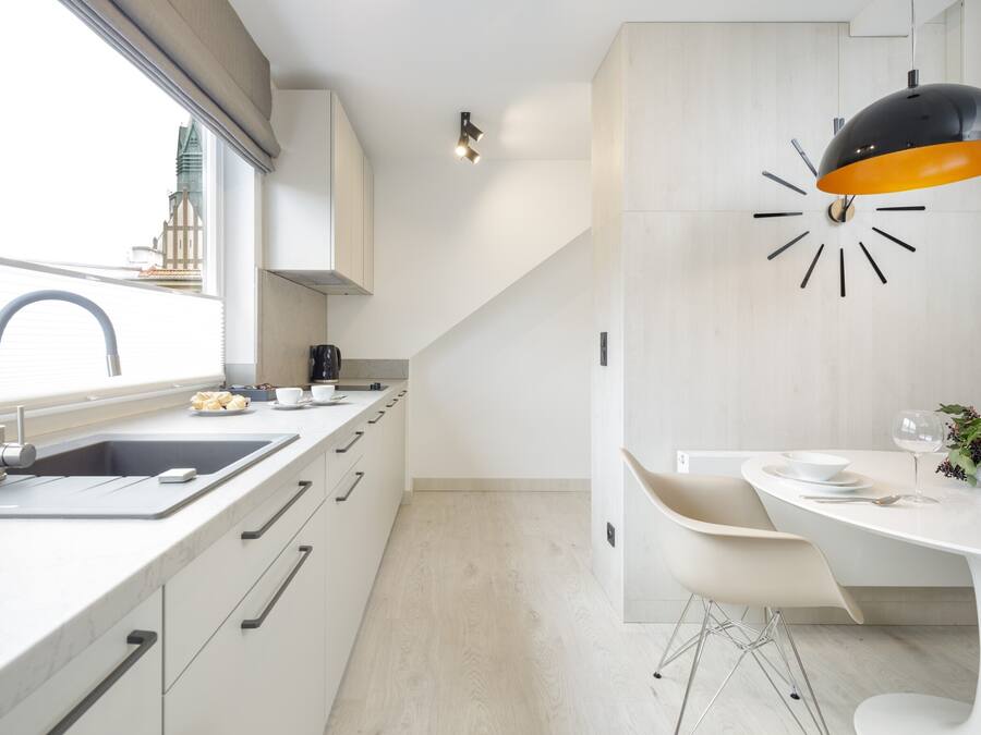 A modern kitchen with a sink, countertop, and a dining area with a table and chairs.
