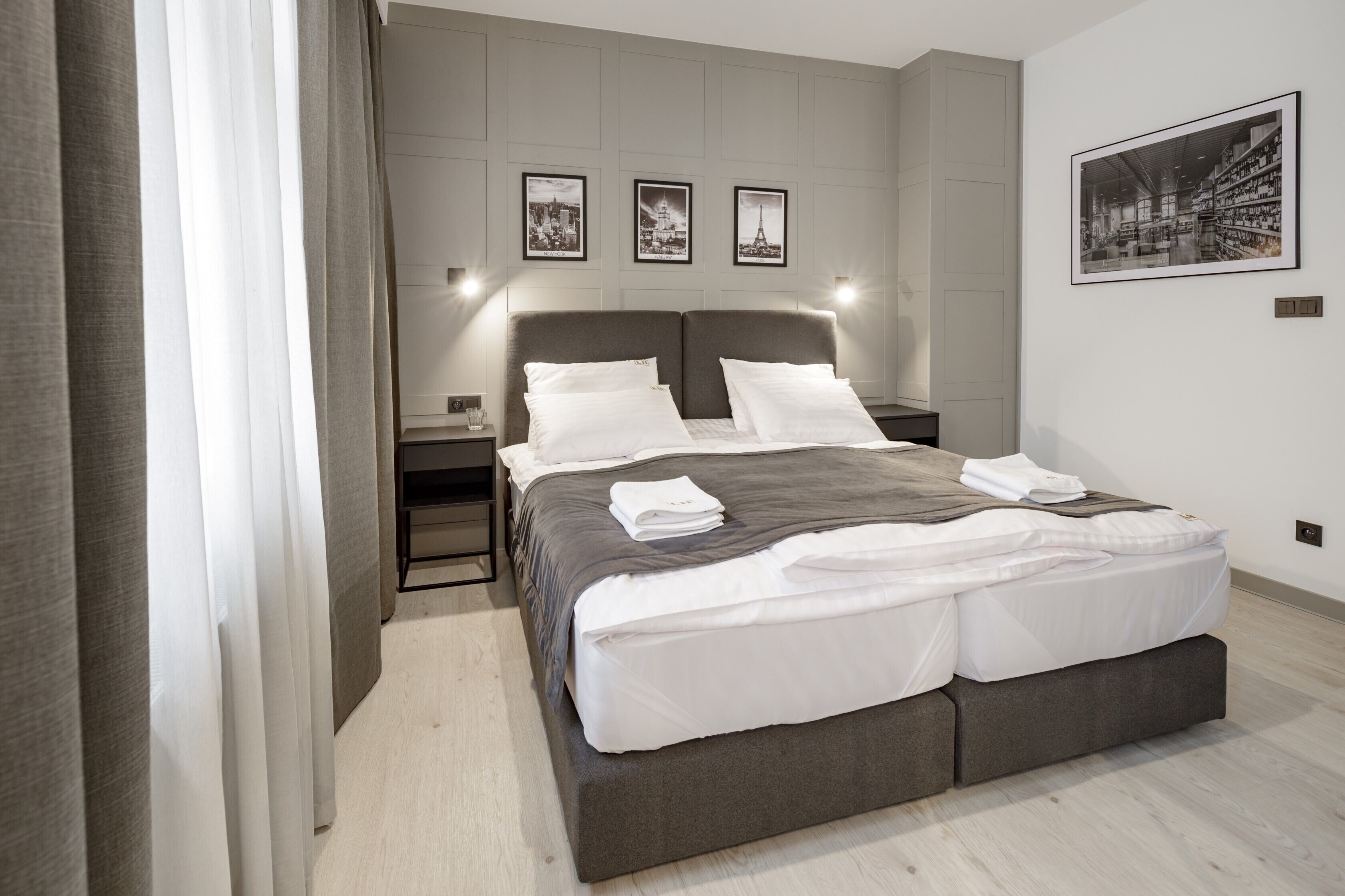 A modern bedroom with a large bed, bedside tables, and framed pictures on the wall.