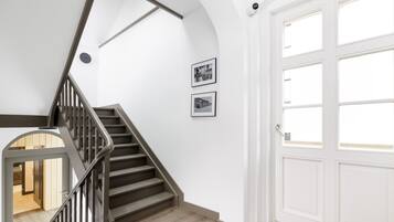 A staircase with a wooden finish, white walls, and two framed pictures.
