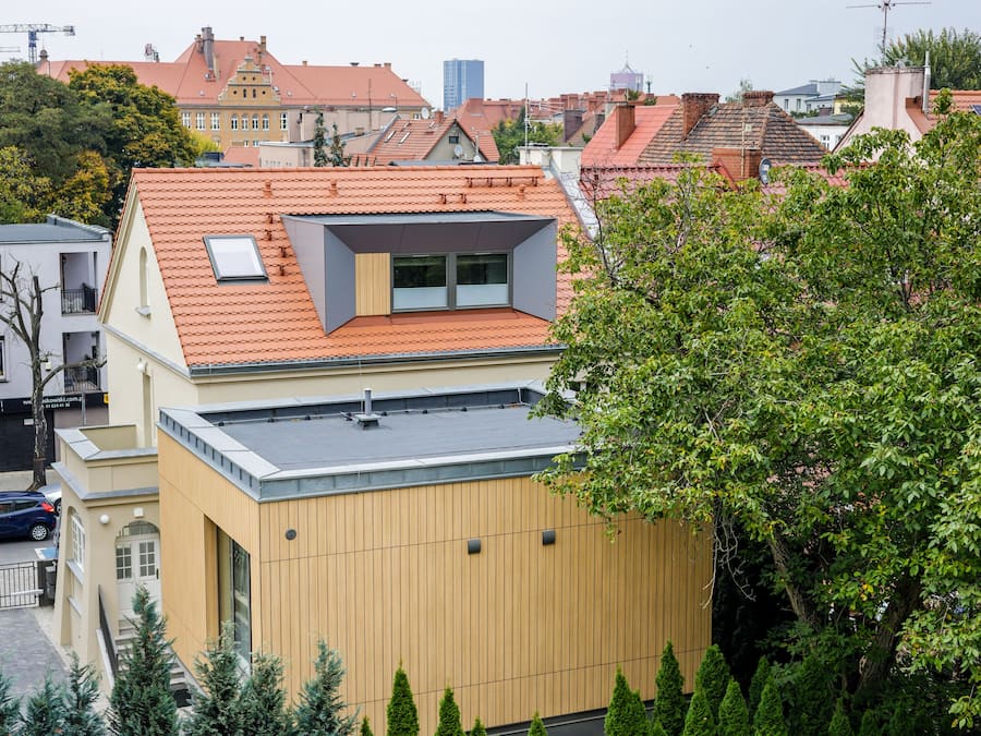 A modern building with a sloped roof, a small skylight, and a visible chimney.