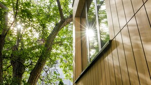 A modern building with large windows and wooden paneling, surrounded by trees. - Apartamenty L11 (Poznan)