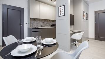 Una cucina moderna con mobili bianchi, un piano di lavoro in granito e un'area pranzo con un tavolo rotondo e sedie bianche.
