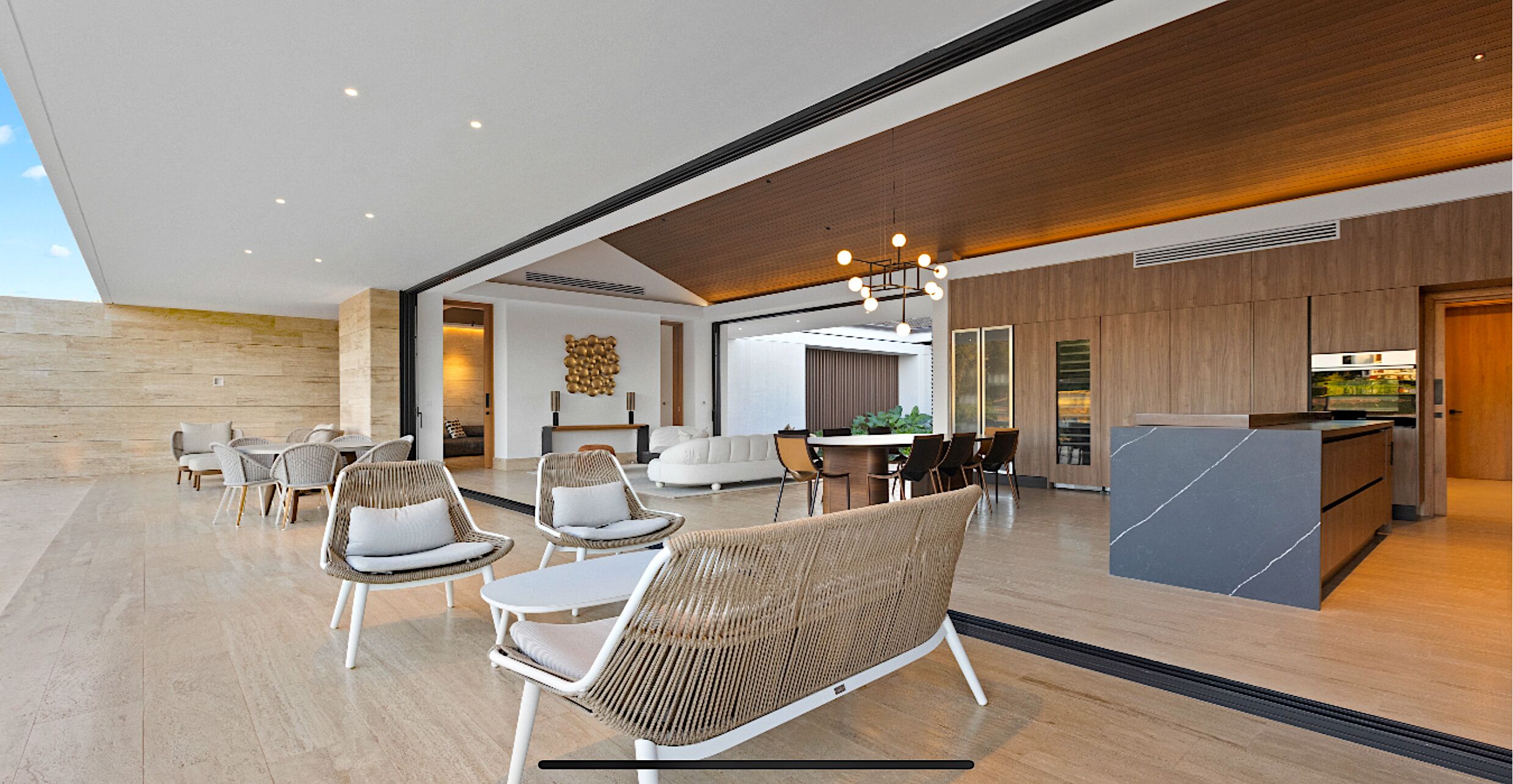 A spacious lobby with a reception desk, seating area with wicker chairs, and a modern kitchen in the background.