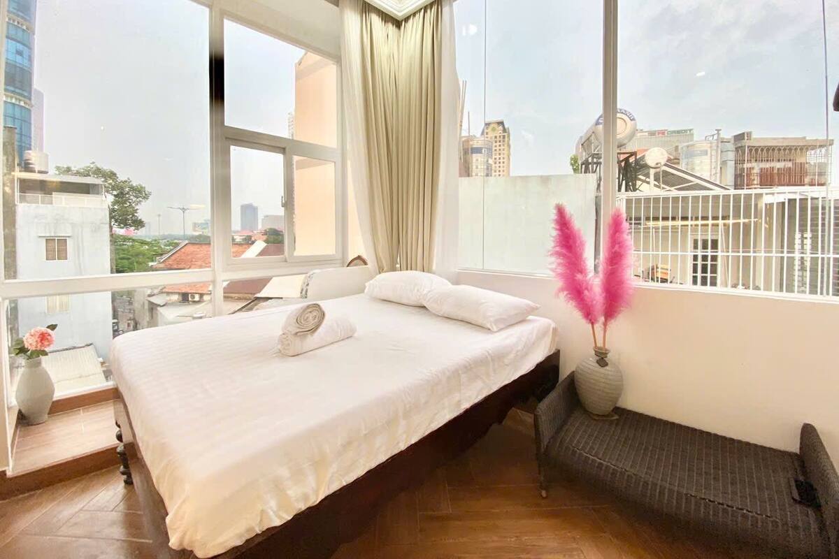 Un dormitorio con una cama grande, vistas de la ciudad y un balcón con barandilla.