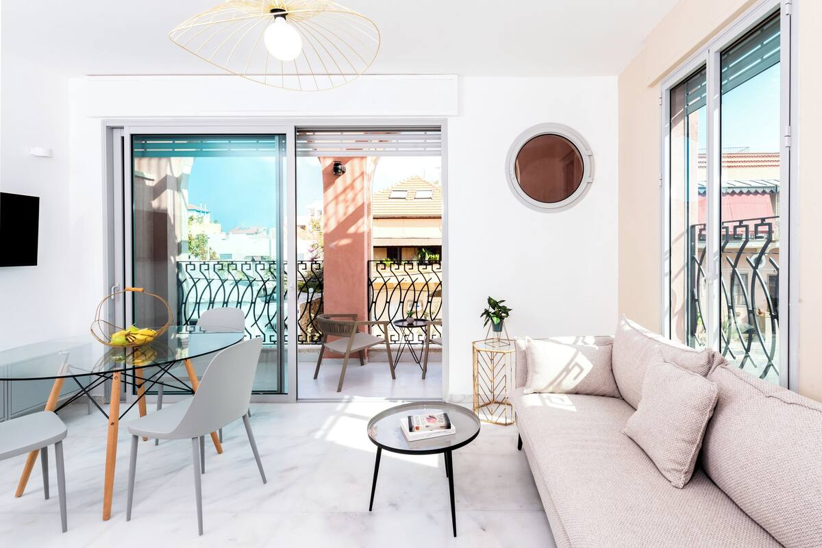 A modern living room with a glass dining table, white sofa, and a round coffee table.