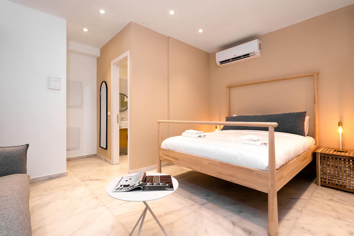 A modern bedroom with a wooden bed, a small round table, and a bedside lamp.
