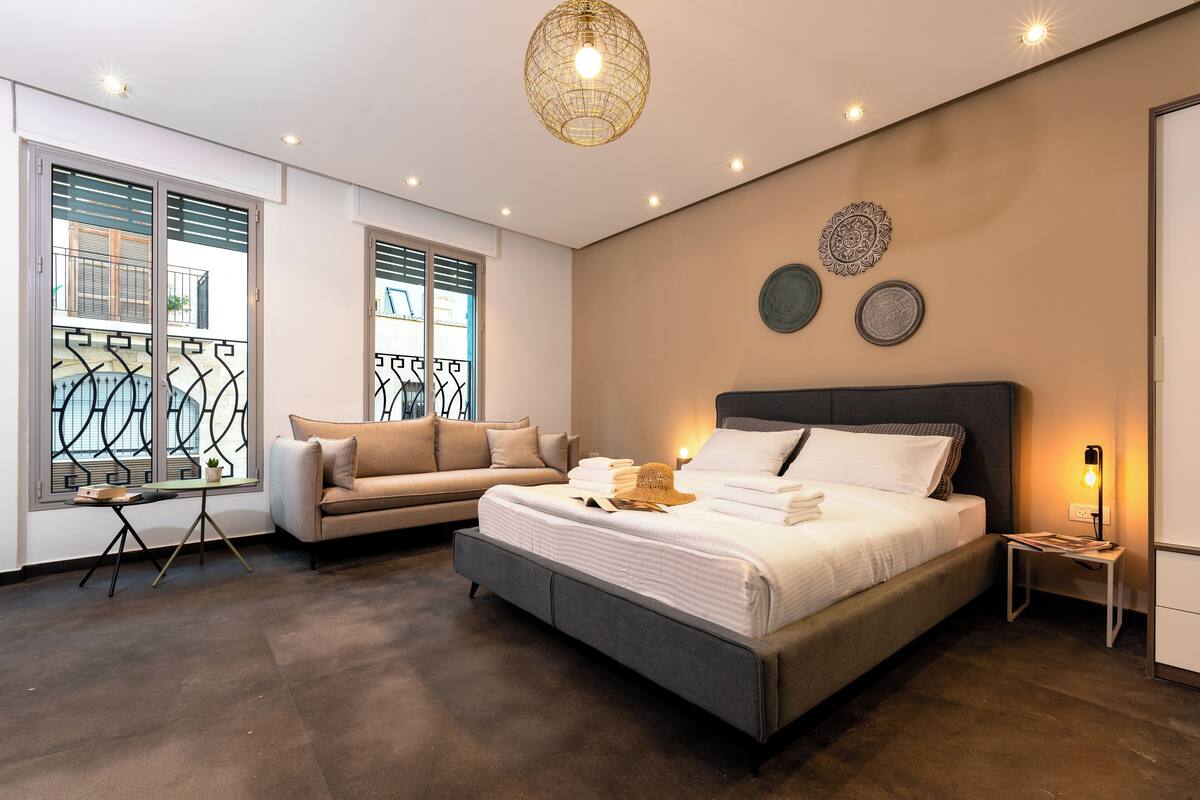 A modern bedroom with a large bed, a sofa, and a small table.