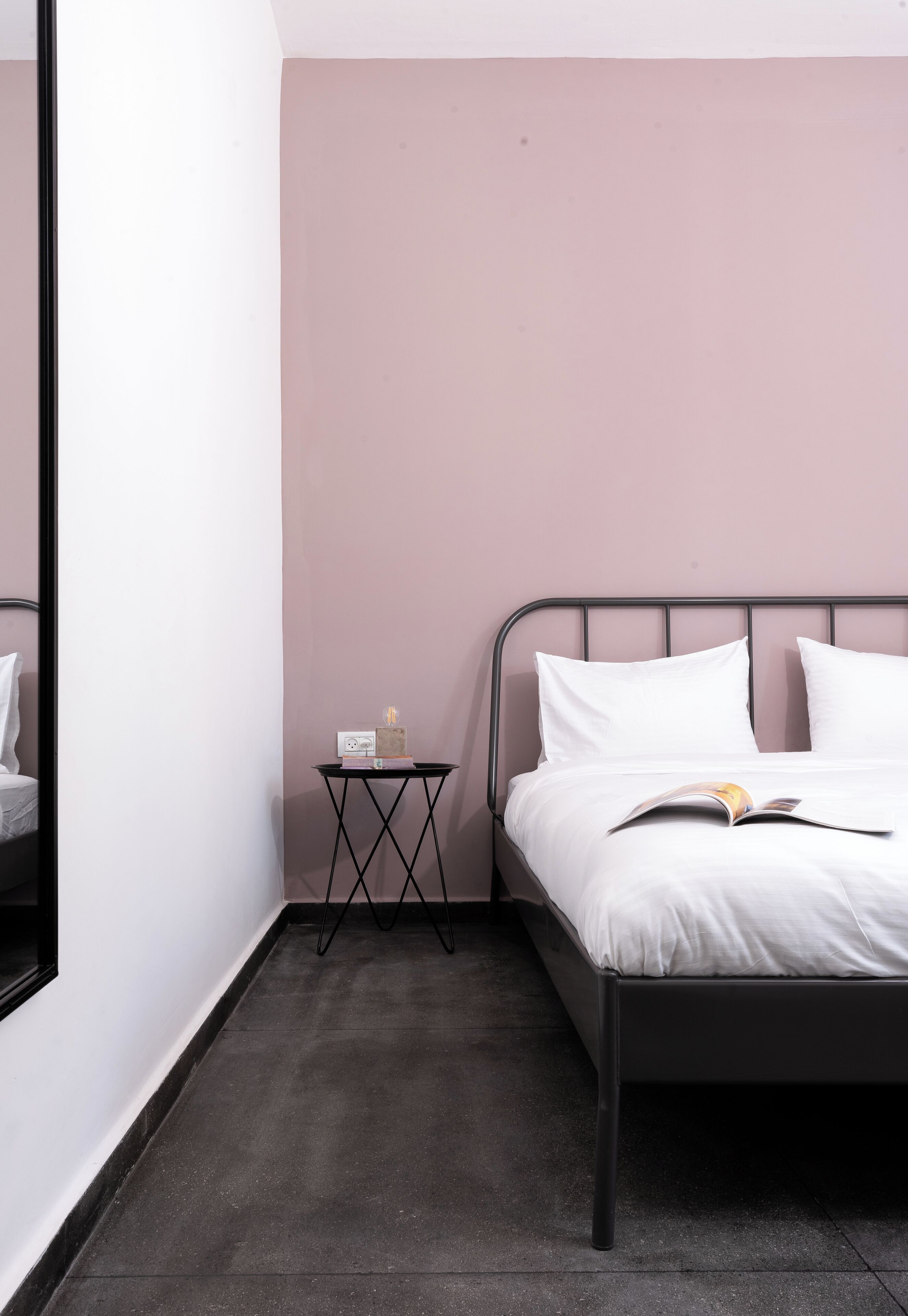 Une chambre à coucher avec un lit, une table de chevet, une petite lampe et un livre.