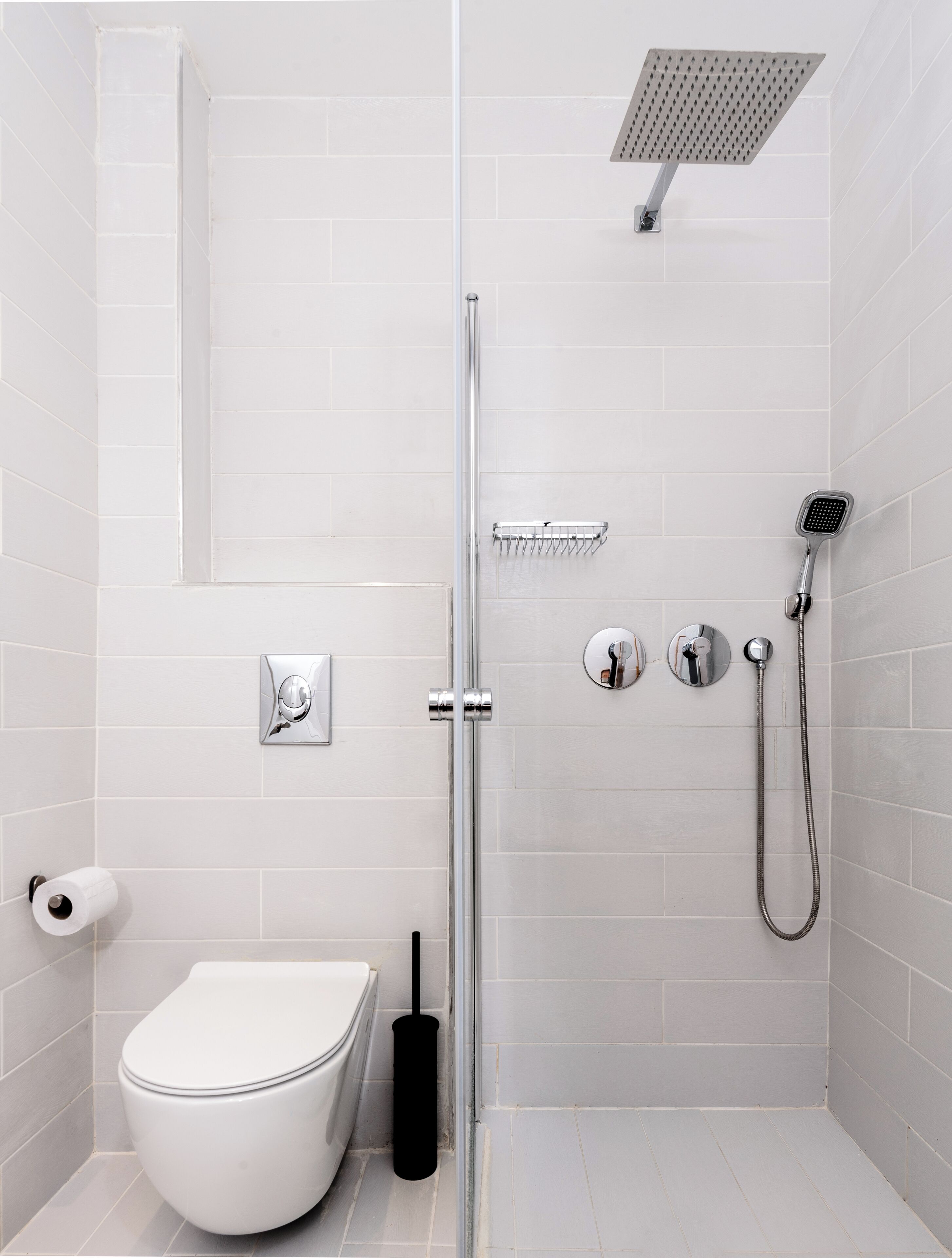 Un baño moderno con ducha envuelta en vidrio, inodoro y ducha de mano.