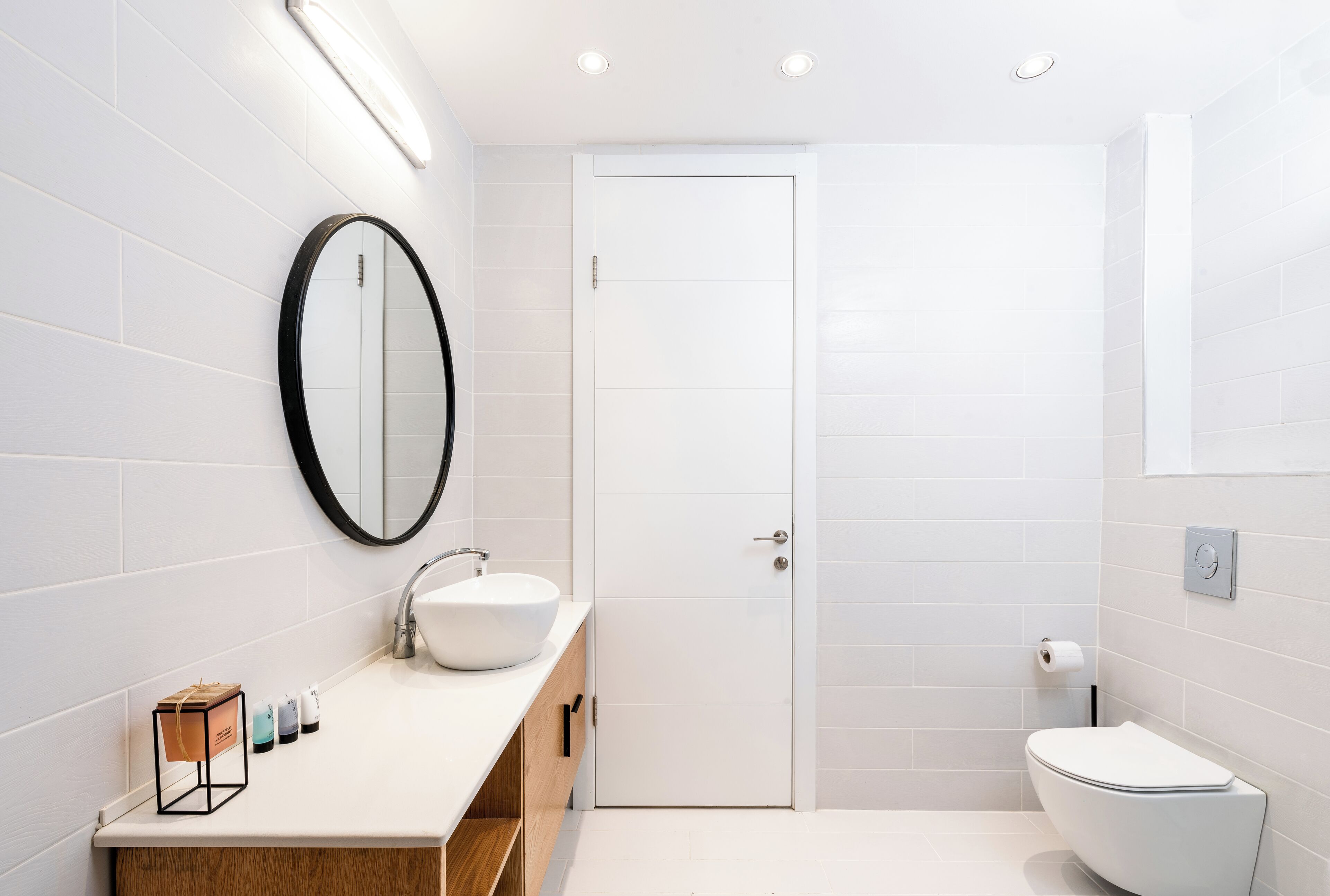 A modern bathroom with a white sink, mirror, and toilet.