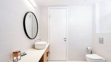 A modern bathroom with a white sink, mirror, and toilet.