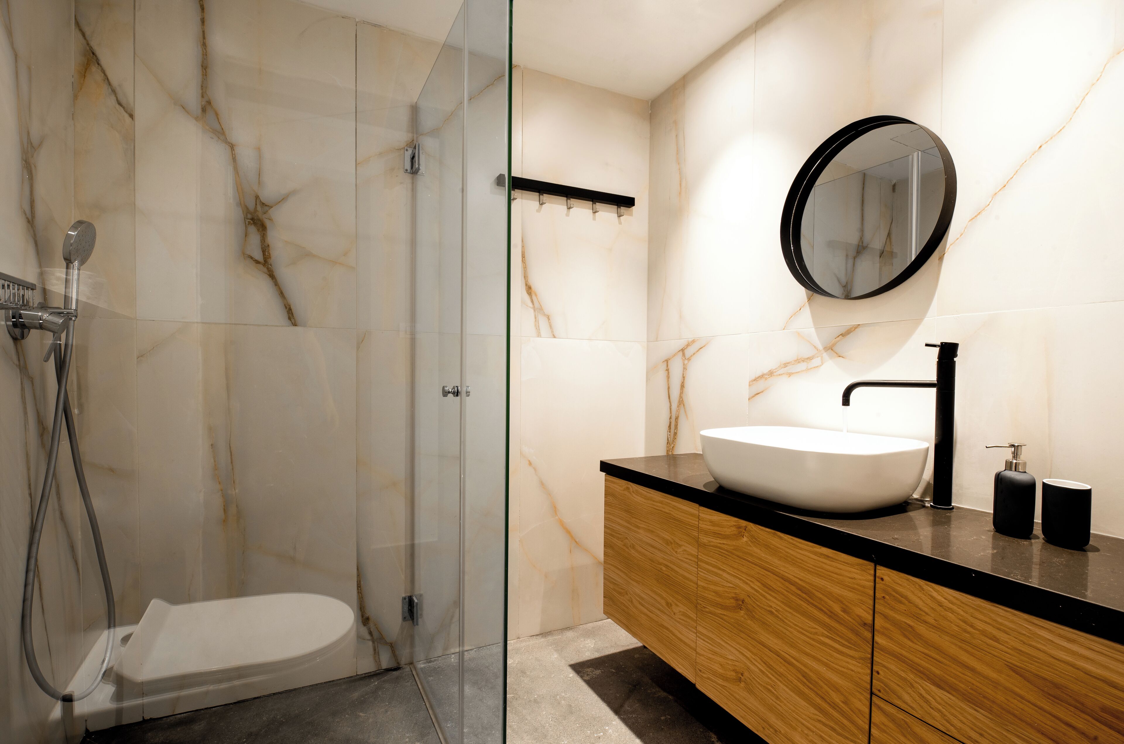 Un baño moderno con ducha de vidrio, lavamanos blanco y tocador de madera.