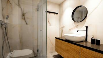 Un baño moderno con ducha de vidrio, lavamanos blanco y tocador de madera.