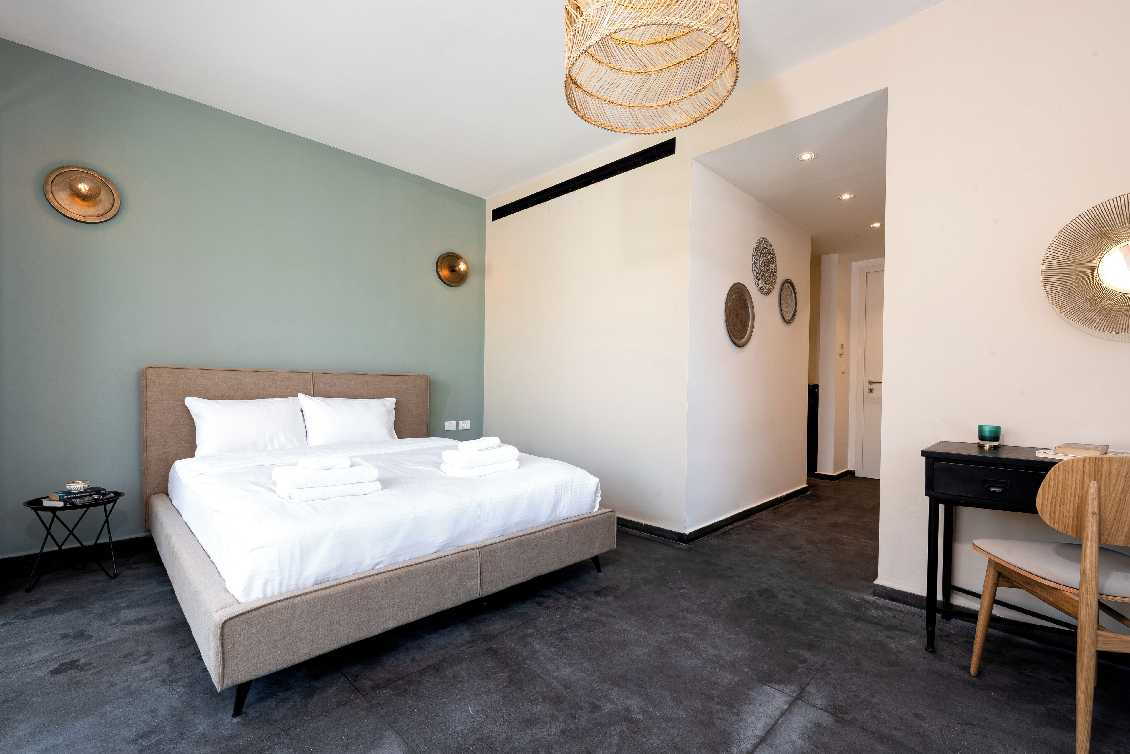 A modern hotel room with a large bed, a desk, and a chair.