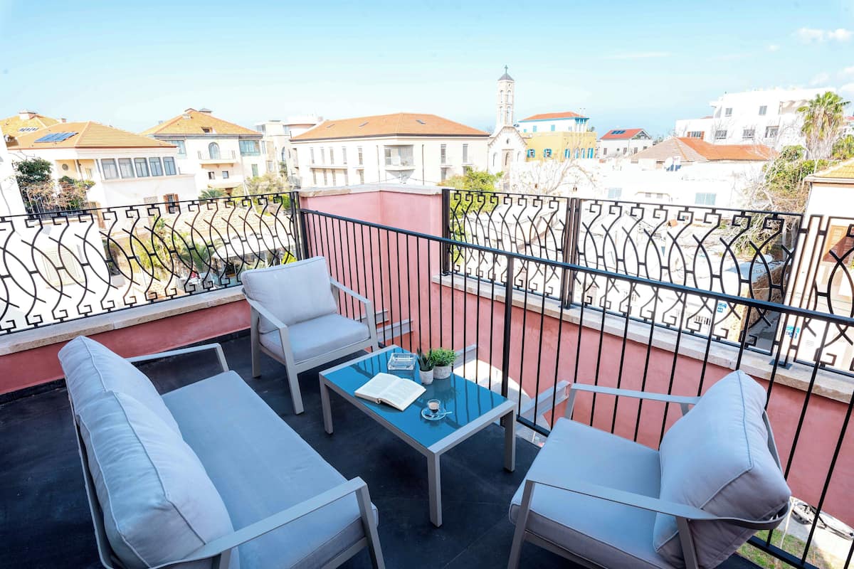 A balcony with a table, two chairs, and a sofa.
