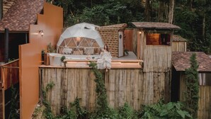 Entorno rústico al aire libre con una estructura de madera, una tienda de forma abovedada y un pequeño edificio de madera.