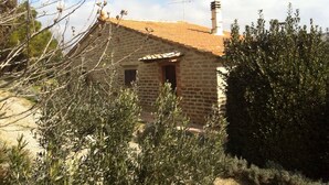 Un edificio de piedra con tejado de baldosas, una chimenea y una ventana pequeña.
