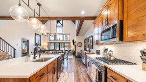 A spacious kitchen with wooden cabinets, a large island, stainless steel appliances, and pendant lighting.