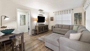 Una sala de estar con sofá, televisión y comedor con mesa y sillas.