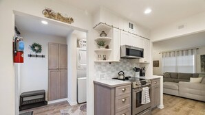 Cocina compacta con electrodomésticos modernos, comedor y sala de estar con sofá.