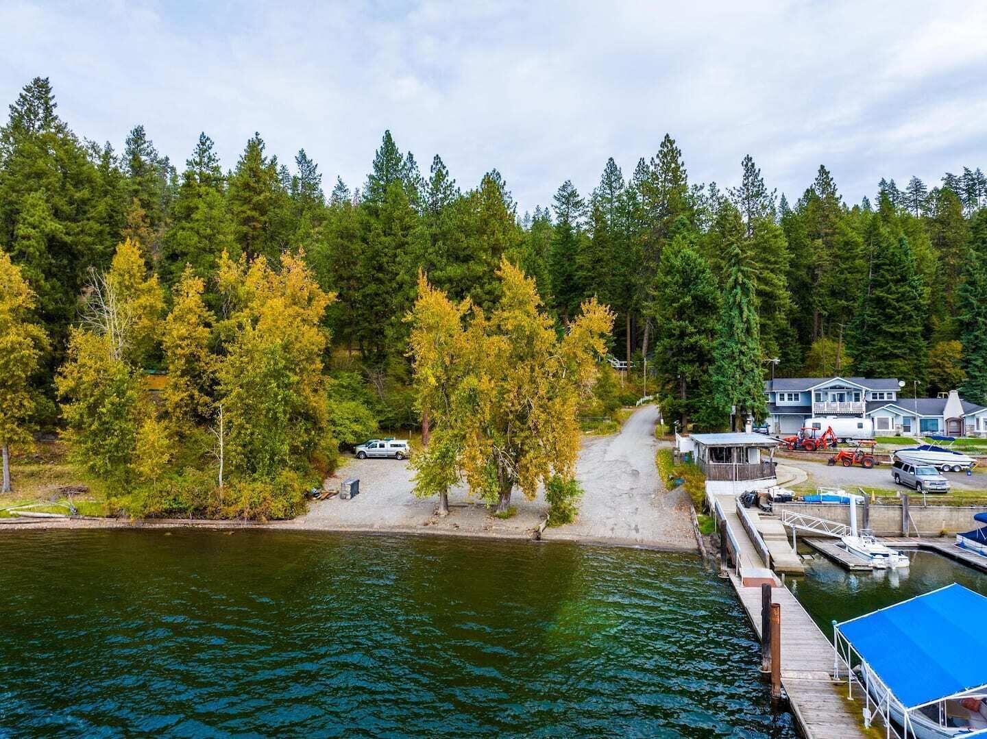 Uma propriedade à beira do lago com um cais, uma cabana pequena e uma casa com um barco atracado perto.