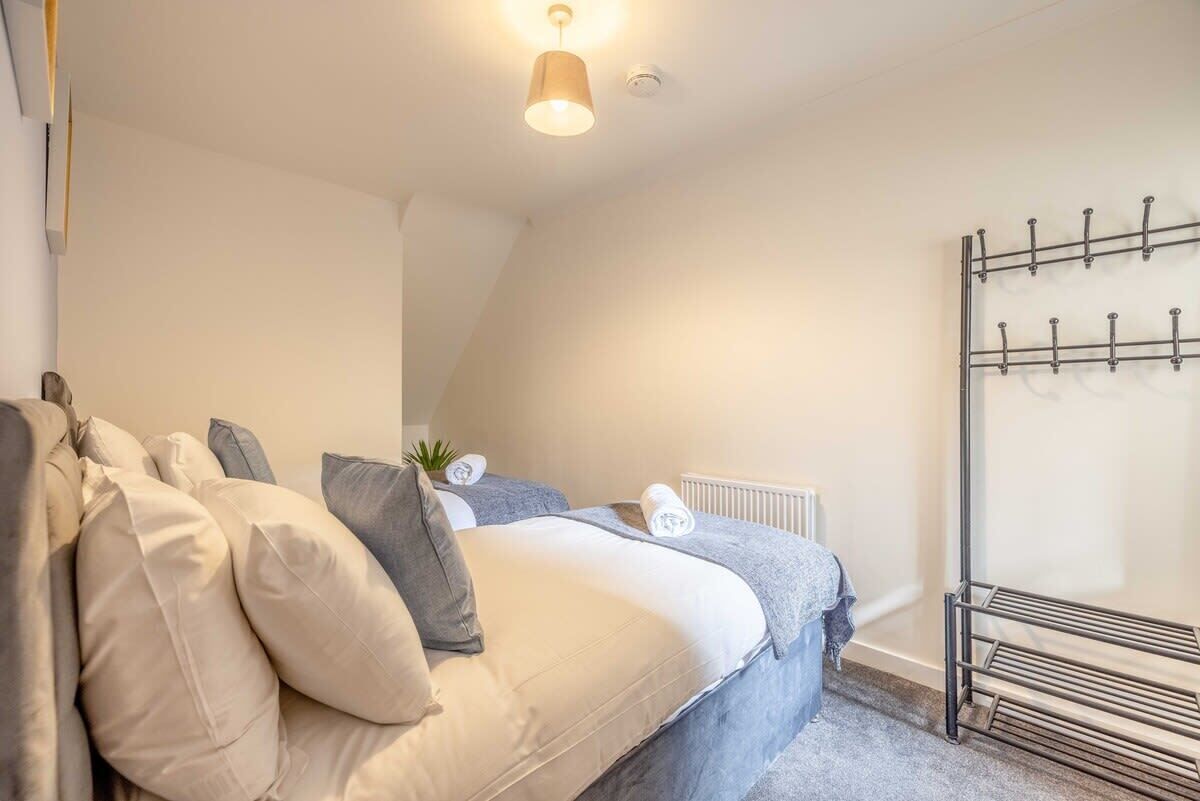 A bedroom with a bed, pillows, a radiator, and a metal drying rack.