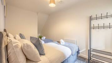 A bedroom with a bed, pillows, a radiator, and a metal drying rack.