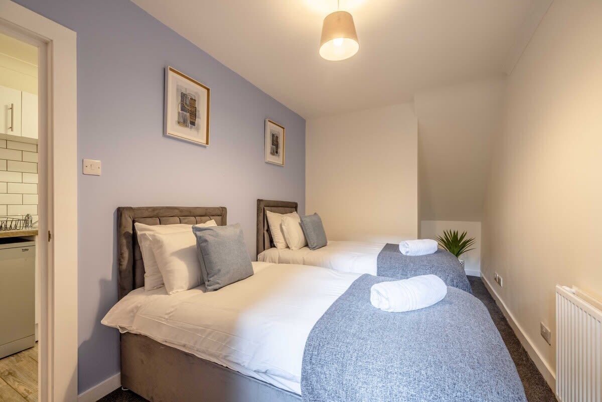 Ein Schlafzimmer mit zwei Betten, einem Heizkörper und einer kleinen Pflanze.
