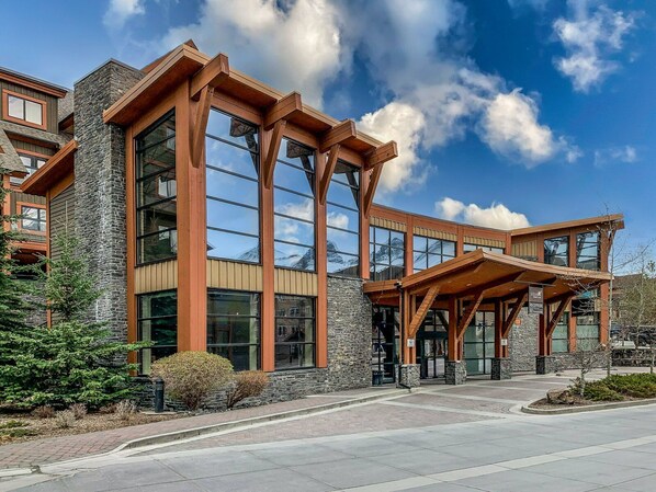 A modern building with large windows and a stone facade. - Gorgeous Mountain Condo - Pool & Hot Tub (Canmore)
